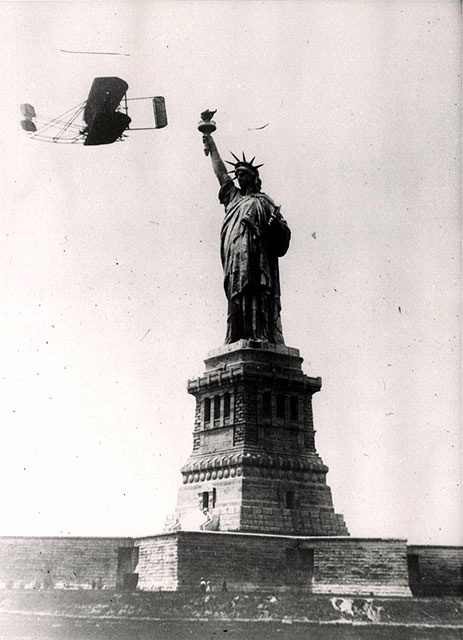 Wright brothers' airplane above Statue of Liberty.